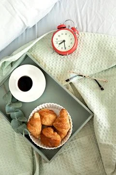Alarm clock and coffee cup at bed in sunny room. Easy morning start, positi.. Stock Photos