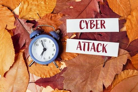 Alarm Clock and Cyber Attack Text on Autumn Leaves Stock Photos