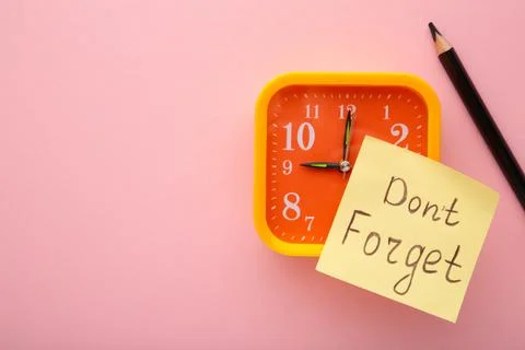 Alarm clock and reminder note with phrase Don't forget on pink background Stock Photos