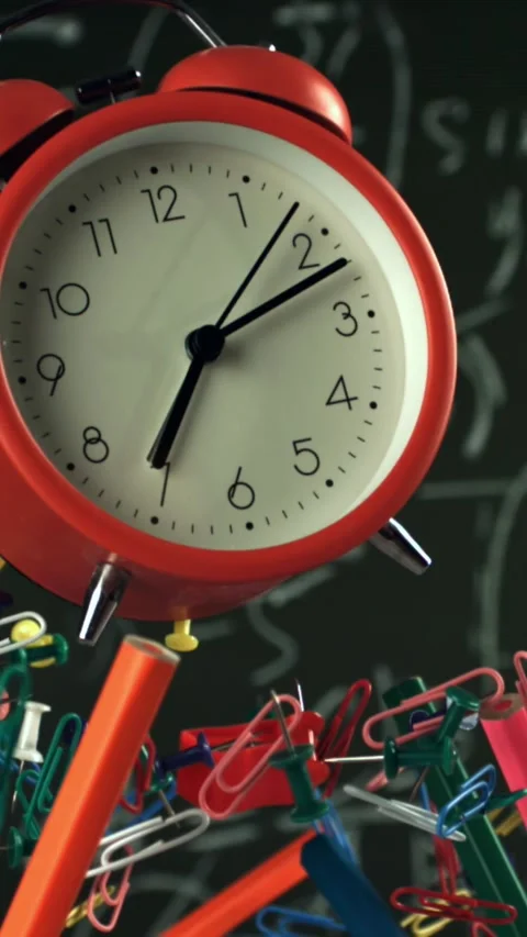 Alarm clock and school tools soaring up against the blackboard background Stock Footage 335372889