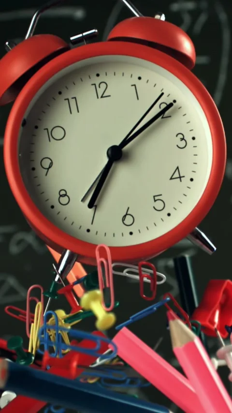 Alarm clock and school tools soaring up against the blackboard background Stock Footage 335373176