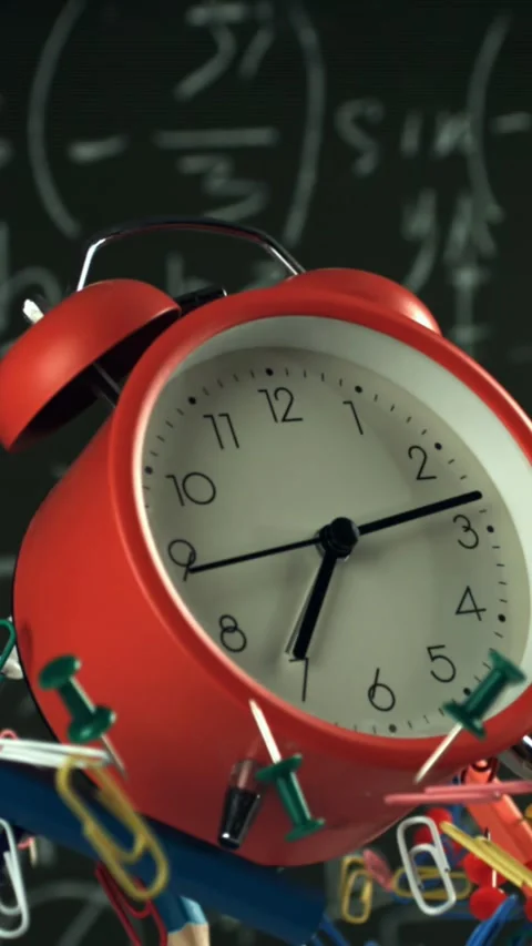 Alarm clock and school tools soaring up against the blackboard background Stock Footage 335378074