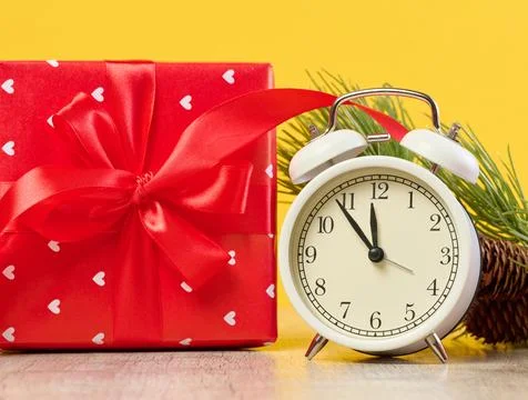 Alarm clock and stack of red gift boxes on yellow background 스톡 사진
