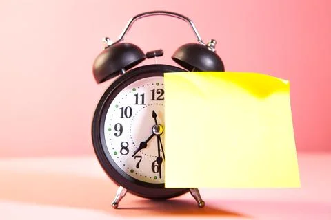 Alarm clock and sticky note with copy space on pink background Stock Photos