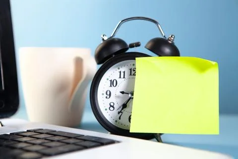 Alarm clock and sticky note with coffee cup on blue background. Foto stock