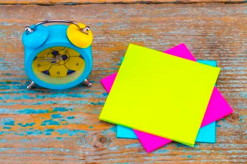 Alarm clock and a  sticky notes with empty space for a text on wooden backgro Stock Photos