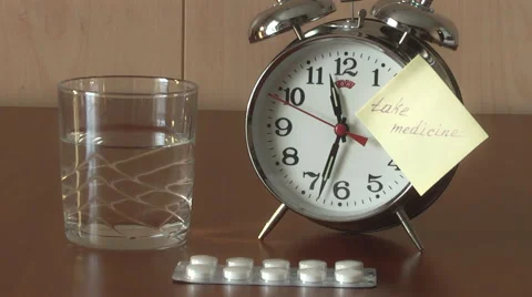 An alarm clock and a yellow note with this text: "take medicine" Stock Footage 47292525