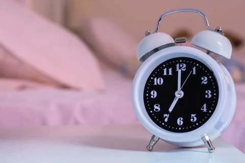 Alarm clock on the bed in bedroom, retro style Stock Photos