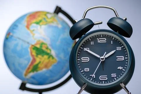 Alarm clock with bells in front of a world globe Stock Photos