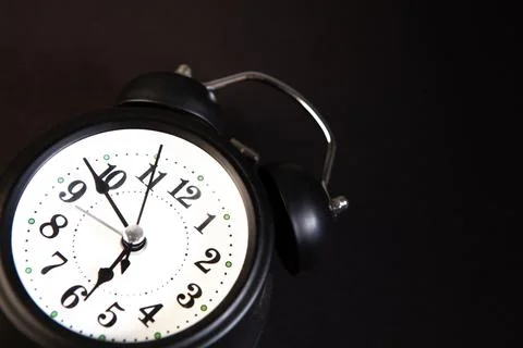 Alarm clock on black background. Time concept. Close up. Stock Photos