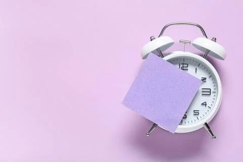 Alarm clock with blank sticky note on lilac background. Time management conce Stock Photos