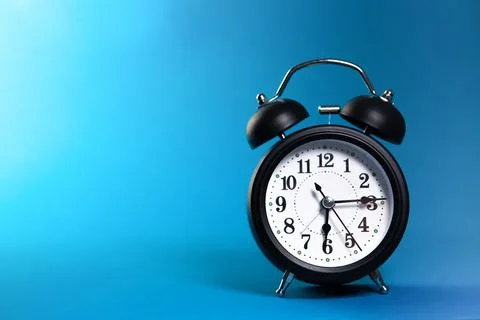 Alarm clock on blue background. Time concept. Close up. Stock Photos