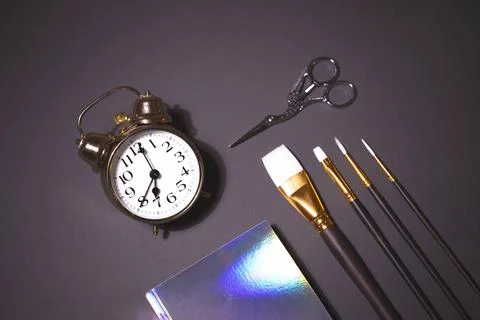 Alarm clock, brush set, scissors and holographic notepad on the grey background Stock Photos