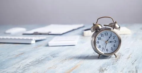 Alarm clock with business objects on the desk. Stock Photos