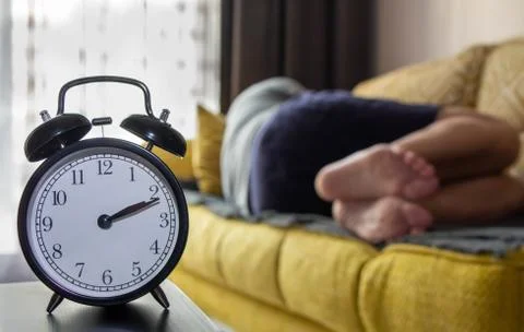 Alarm clock close-up on a background of a sleeping man. Stock Photos