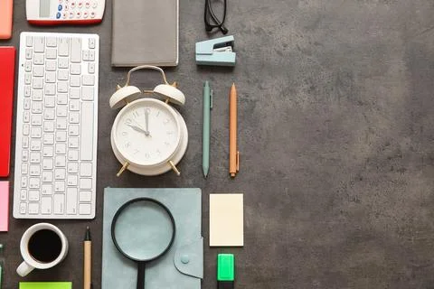 Alarm clock with computer keyboard, cup of coffee and office supplies on dark Stock Photos