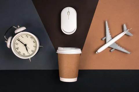 Alarm clock, computer mouse, cup and airplane on a paper background, top view. Stock Photos