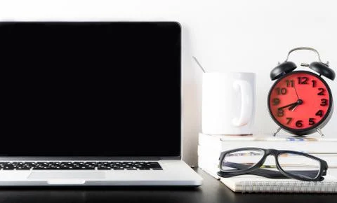 Alarm clock with Computer on office table Stock Photos