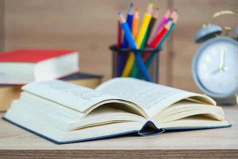 Alarm clock on the desk to read Open book in the background selective focus.. Stock Photos