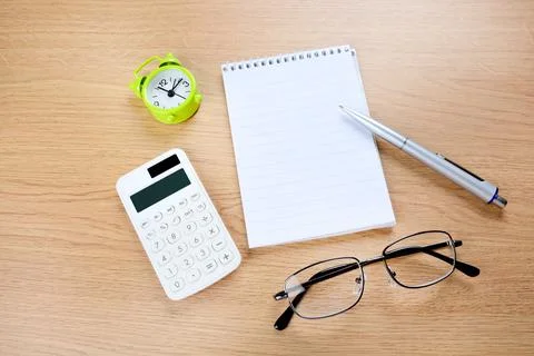 Alarm clock with empty notepad and pen on desk Stock Photos