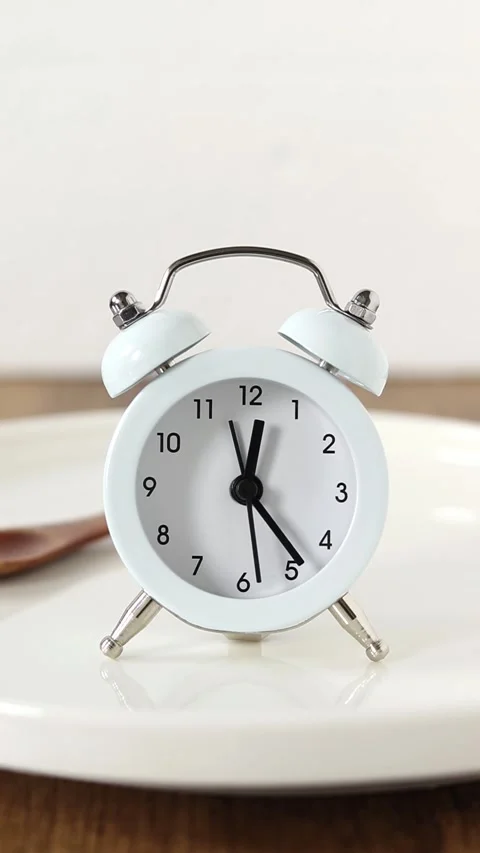 Alarm clock on empty plate and wooden spoon with white background Stock Footage 288015084