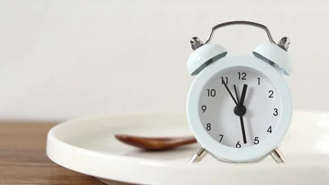 Alarm clock on empty plate and wooden spoon with white background Stock Footage 292424838
