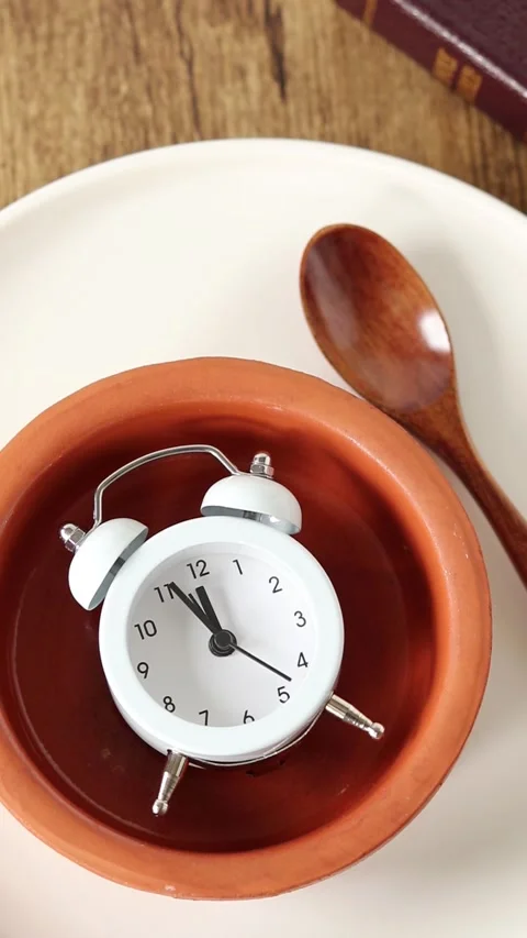 Alarm clock in empty plate with spoon and holy bible book Stock Footage 288015145