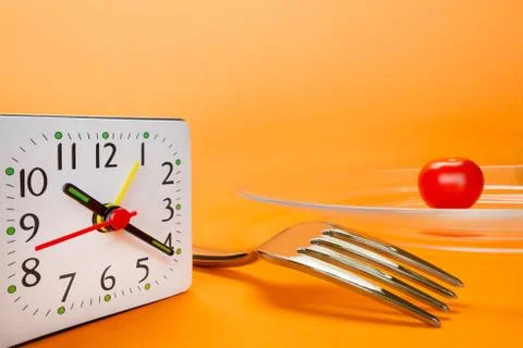 Alarm clock, fork and small cherry tomato Foto stock