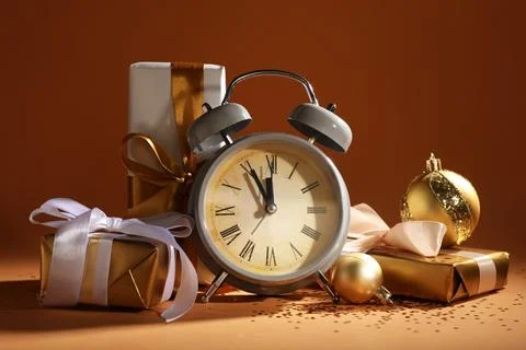 Alarm clock, gift boxes, confetti and Christmas balls on beige table near col Stock Photos