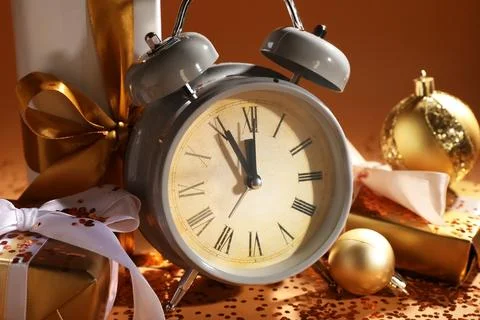 Alarm clock, gift boxes, confetti and Christmas balls on beige table near col Stock Photos