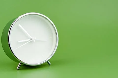 Alarm clock on green background time concept working with time precious time Stock Photos