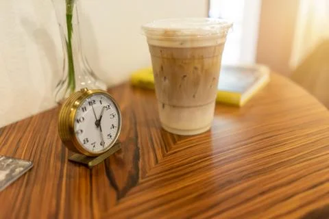 Alarm clock with iced coffee on table at cafe Stock Photos
