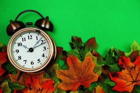 Alarm clock with Maple leaf boder on green background Stock Photos