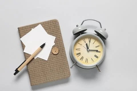 Alarm clock with notebook, sticky notes and pen on grey background. Time mana Stock Photos