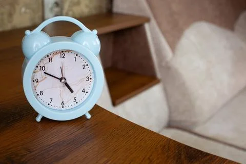 Alarm clock to notify bedtime is on shelf of home sofa Stock Photos