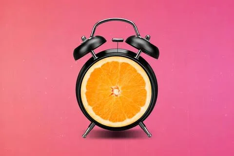 Alarm clock with orange slice face on pink background Stock Photos
