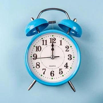 An alarm clock placed on a blue background Stock-Fotos