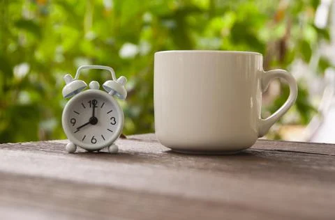 Alarm clock pointing at 8 o'clock with coffee cup on a bench. Copy space conc Stock Photos
