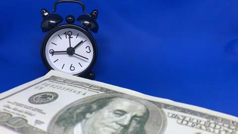 Alarm clock positioned beside a U.S. hundred-dollar bill, Stock Photos