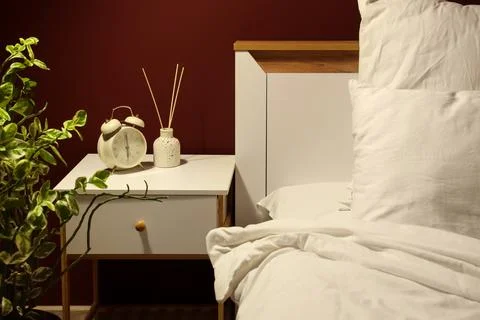 Alarm clock with reed diffuser on nightstand in dark bedroom Stock Photos