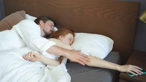 The alarm clock rings while the couple sleeps. Stock Footage 137696011