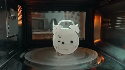 The alarm clock rotates on a plate inside the microwave. 스톡 동영상 141327745
