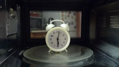 The alarm clock rotates on a plate inside the microwave. 스톡 동영상 141327892