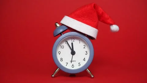 Alarm clock in a Santa's hat on a red background indicating almost 12 o'clock Stock Footage 315412986