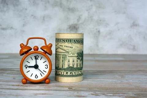 Alarm clock set at 9 o'clock with banknotes on table. Tax time concept. Stock Photos