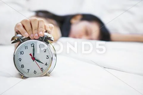 Alarm clock with sleeping female on bed Stock Photos