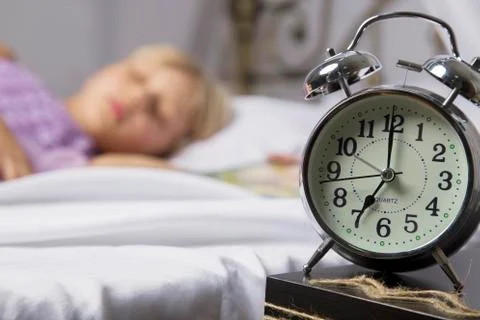 Alarm clock standing on bedside table. Wake up of an asleep young girl stopping Stockfoto's