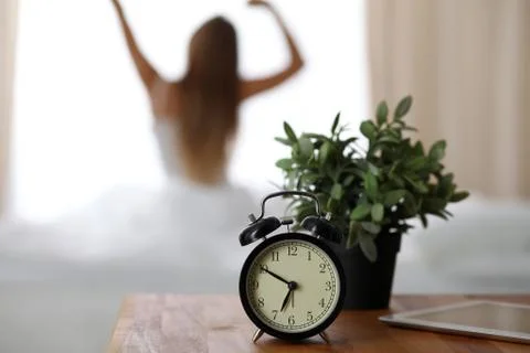 Alarm clock standing on bedside table has already rung early morning to wake up Stock Photos