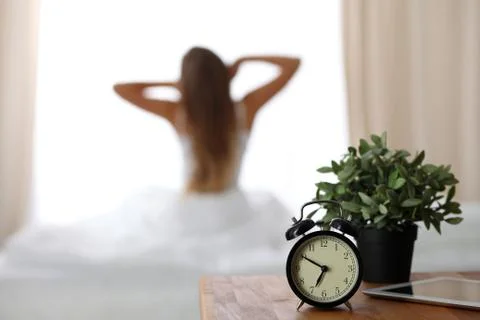 Alarm clock standing on bedside table has already rung early morning to wake up Stock Photos