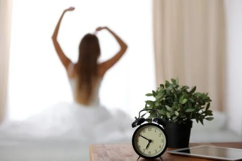 Alarm clock standing on bedside table has already rung early morning to wake up Stock Photos